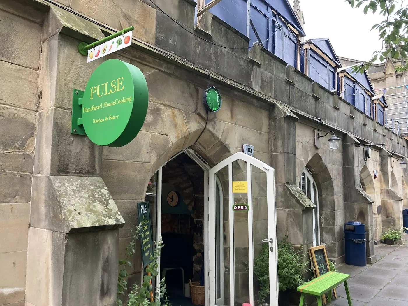 PULSE's round green sign with gold lettering above the stone arch entrance at St John's Church